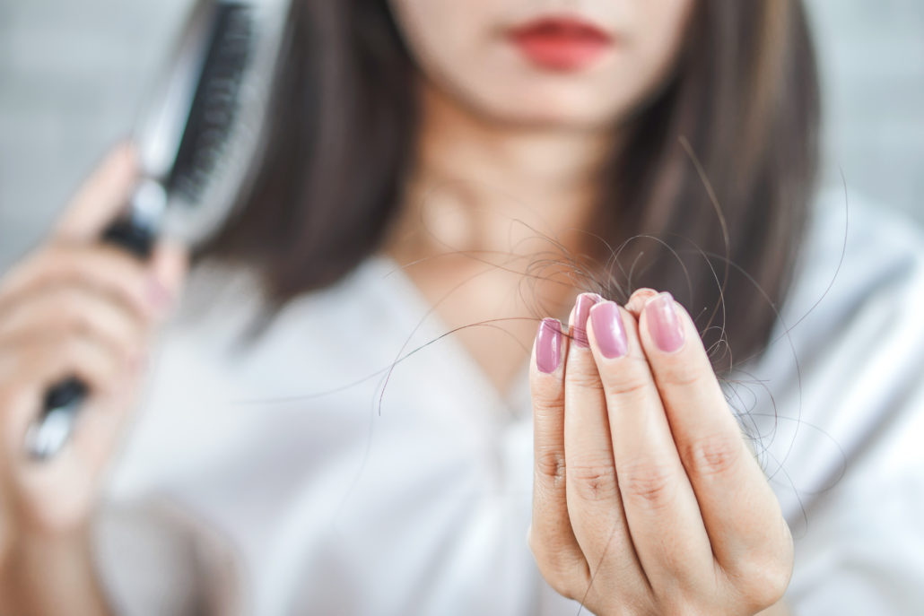 Eine Frau leidet unter Haarbruch und hält ihre ausgefallenen Haare in die Kamera. Unike Kapseln können bei Problemen mit den Haarenhelfen.